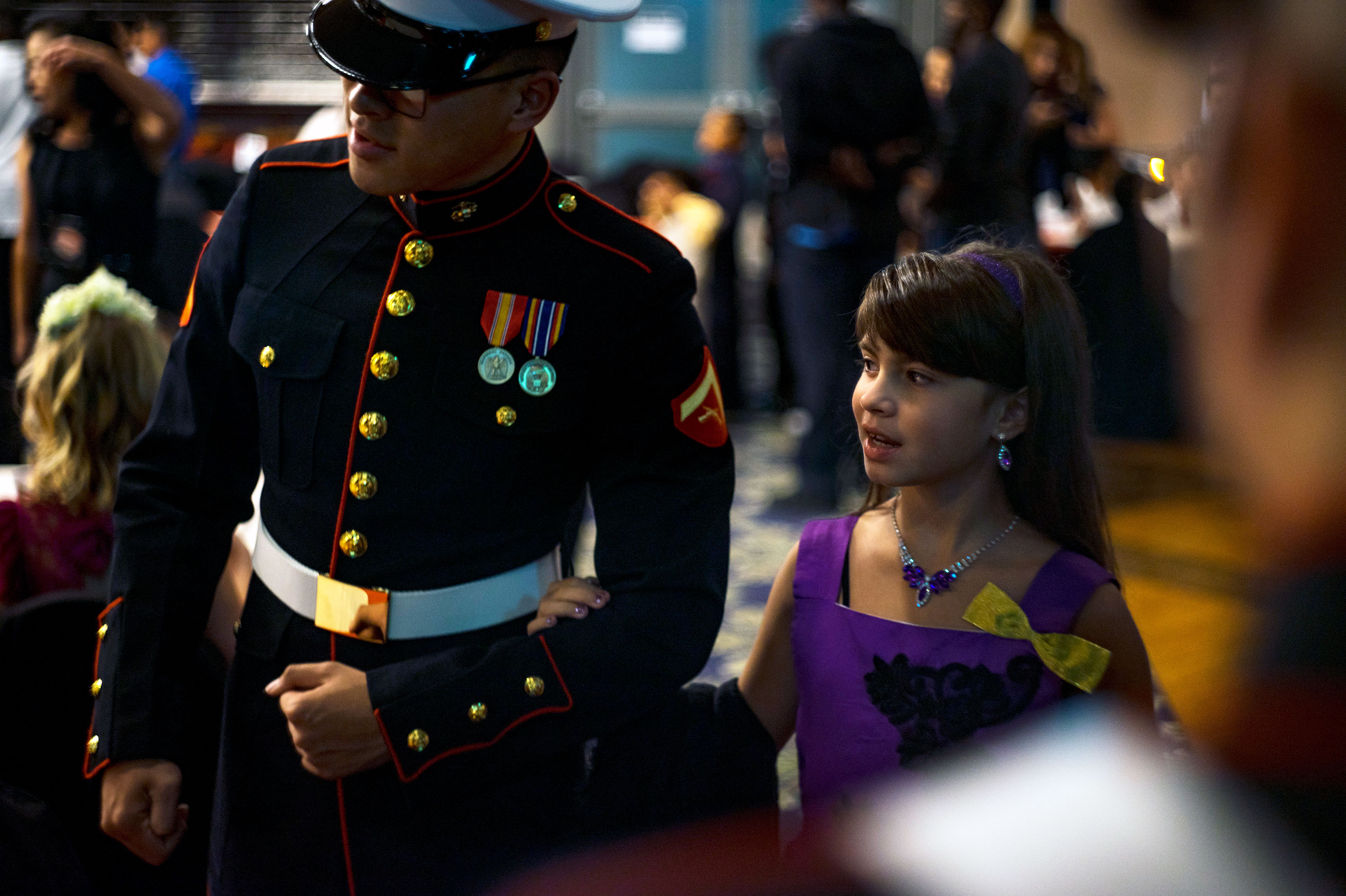 A U.S. Marine escorts a child to her seat during the Seventh Annual Mini Marine Corps and Navy Ball at Marine Corps Air Station Iwakuni, Japan, Oct. 21, 2017.  (U.S. Marine Corps/Donato Maffin)