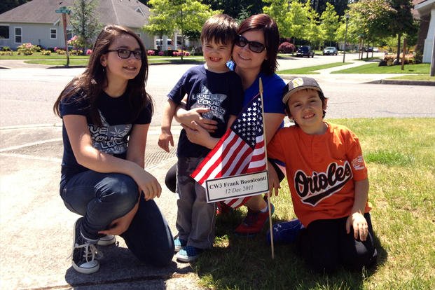 Kryste Buoniconti and her children pose with a sign and flag honoring her husband, Frank. (Courtesy of Kryste Buoniconti)