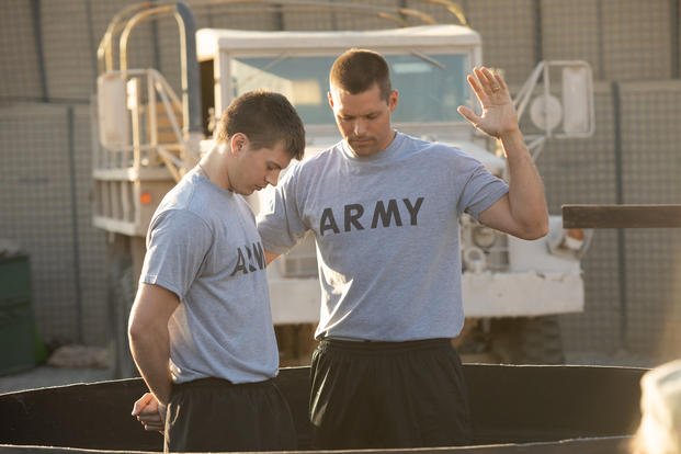R to L: Chaplain Darren Turner (Justin Bruening) performs an Easter Baptism service in Iraq with Lance Bradley (Tanner Stine) in "Indivisible." (Photo courtesy of © 2018 Provident Films LLC and The WTA Group, LLC.)