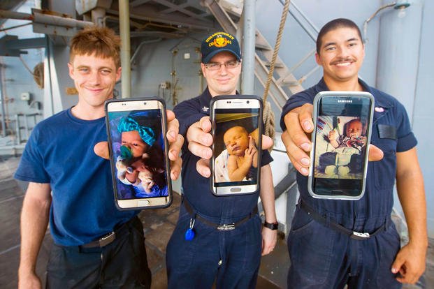 Seaman Cody Slone, left, Petty Officer 1st Class Joshua Morcom and Seaman Chase Marr, show imagery of their newborn babies from their cell phones aboard the guided-missile cruiser USS Monterey (CG 61).  (U.S. Navy/William Jenkins)