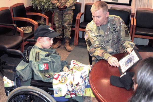 Drake Quibodeaux, 8, who suffers from diffuse intrinsic pontine glioma, a non-operable brain tumor for which there is no cure, receives a certificate and cap from Brig. Gen. Patrick D. Frank, commander, Joint Readiness Training Center and Fort Polk, during a visit March 1. Quibodeaux was promoted to General of the Fort Polk Army for the day. (Chuck Cannon/US Army)