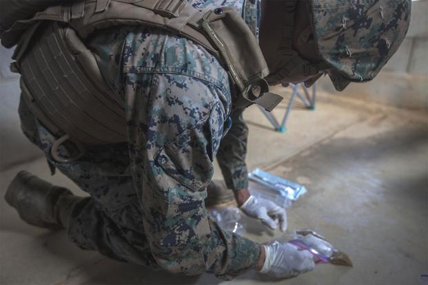 U.S. Marine Cpl. Carlos Ramos gathers forensic material during tactical site exploitation training at Combat Town, Okinawa, Japan, Sept. 12, 2018.. (U.S. Marine Corps/Pfc. Kindo Go)