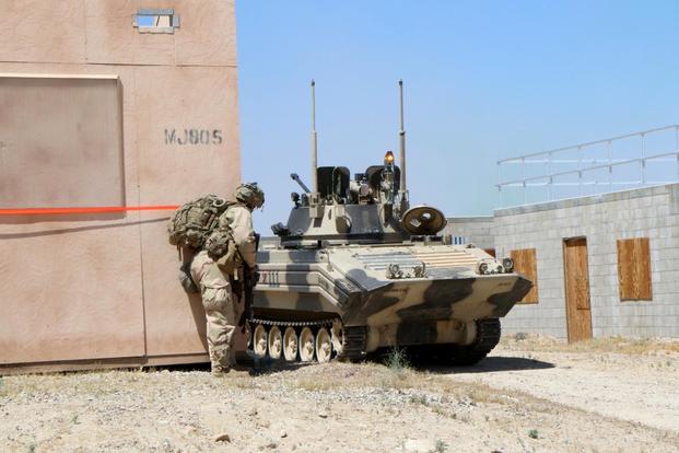 A soldier with the 3rd Infantry Division’s 2nd Armored Brigade Combat Team peers around a corner during a May 8 urban training battle at the National Training Center at Fort Irwin, California. The opposing force (OPFOR) armored vehicle has a flashing amber light indicating that it has been knocked out during the battle. Matthew Cox/Military.com