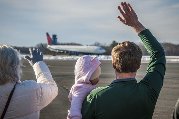 family waving goodbye to an airplane