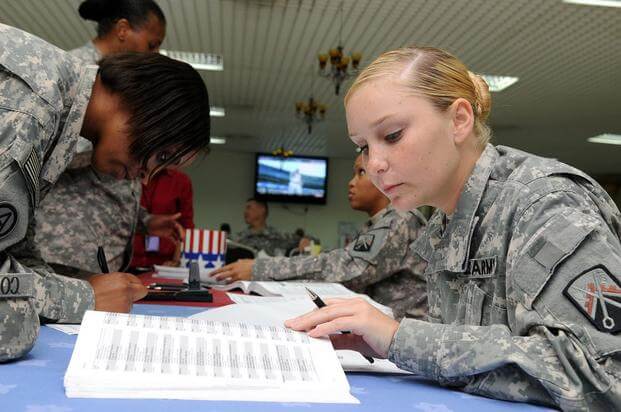 Soldiers fill out their absentee ballot forms at Camp As Sayliyah, Qatar.
