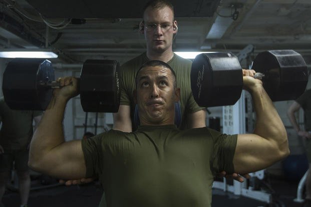 A Marine performs shoulder presses.