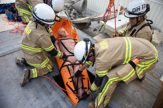 Ohio National Guard firefighters use ropes to extract a simulated trapped building collapse victim.