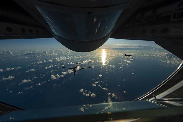 Two B-1B Lancers fly in formation behind a KC-135 Stratotanker.