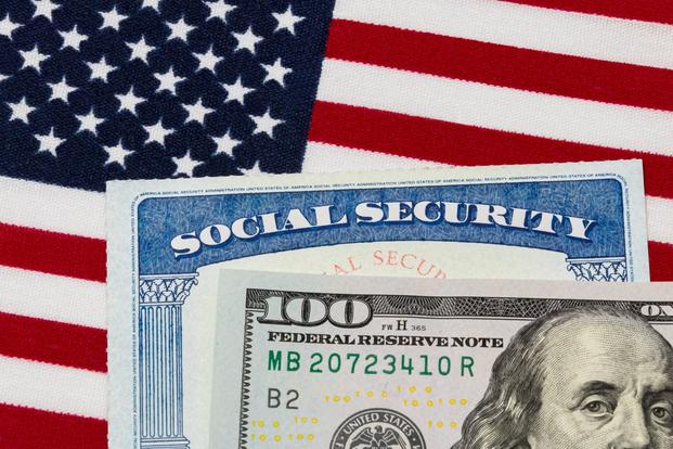A $100 bill with a Social Security card and the Amerian flag.