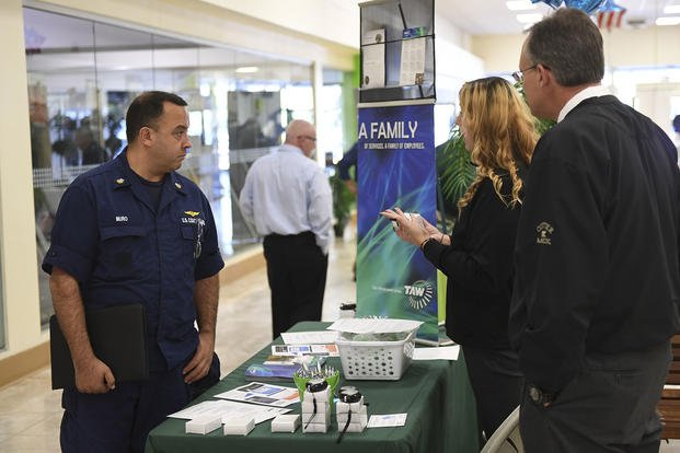 A petty officer first class speaks with training managers during a veterans and military job and resources fair.