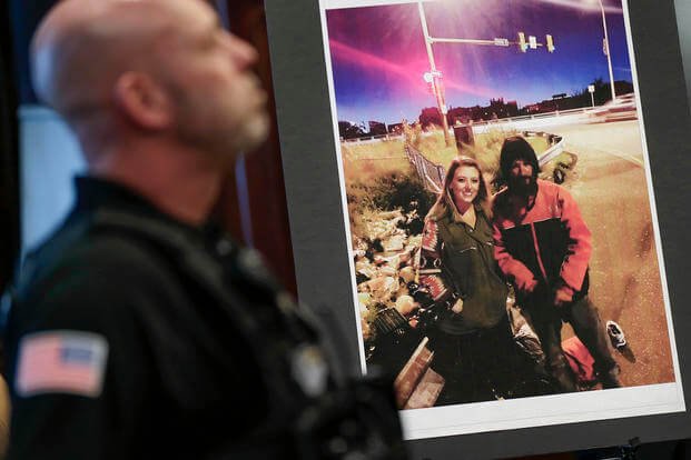 A law enforcement official stands next to a picture of Katelyn McClure and Johnny Bobbitt Jr., on display.