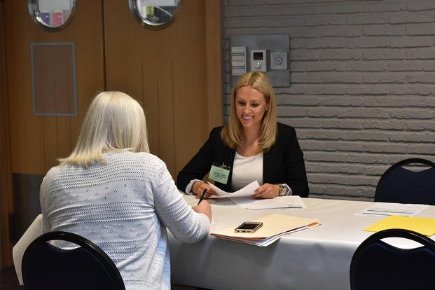 Claudia Toles, Civilian Personnel Advisory Center employee, reviews a candidate's paperwork during the Benelux Employment and Career Expo on SHAPE, Belgium.
