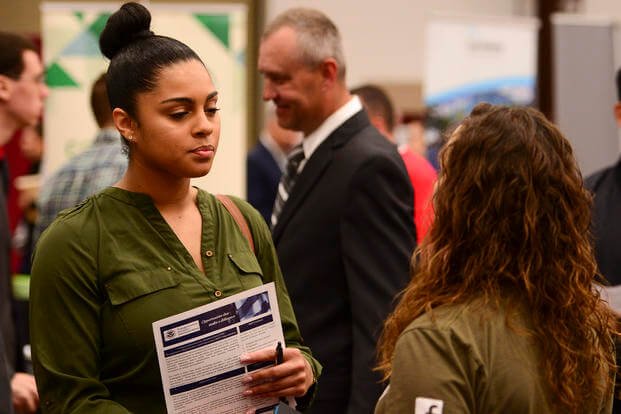 Personnel Specialist 2nd Class Kendra Velasquez speaks with a representative from Facebook during a job fair hosted by The Fleet and Family Support Center at the Kitsap County Fairgrounds in Silverdale, Wash.