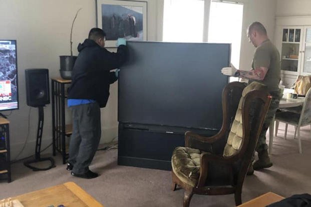 Sgt. 1st Class Rey Bagorio (left) and Capt. Tony Storey, both assigned to the Warrior Transition Battalion, Joint Base Lewis McChord, Washington, work together to move a television as they prepare a room for a homeless veteran. 
