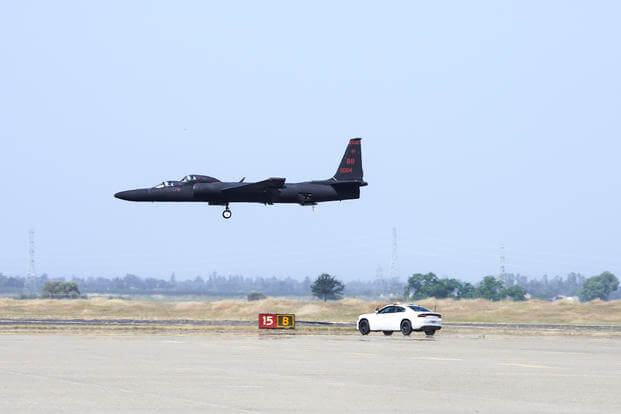 While a U-2 makes its final approach, the chase car driver waits to zoom into position. 