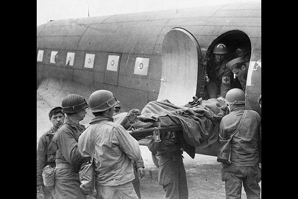 Soldiers and medics load a wounded comrade onto a C-47 Skytrain for transport from France to England during the Brittany Campaign. (Photo: AFMS Historian’s Office)