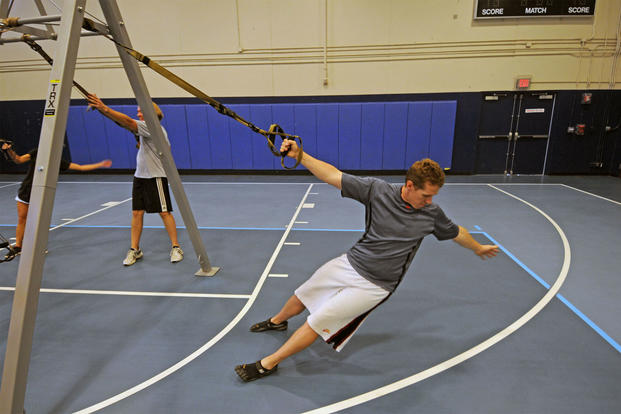 A recreation assistant performs a Total Body Resistance Exercise (TRX) upper-body exercise. 