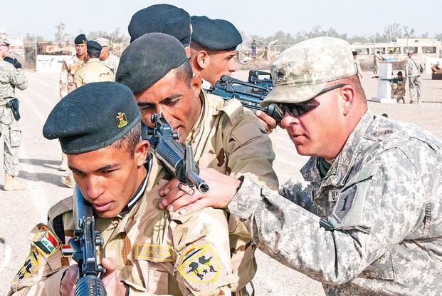 Sgt. David Kappel (right), an infantry trainer assigned to 1st Armored Brigade Combat Team, 1st Infantry Division, adjusts the rifle of an Iraqi army trainee Jan. 7 at Camp Taji, Iraq. (U.S. Army photo)