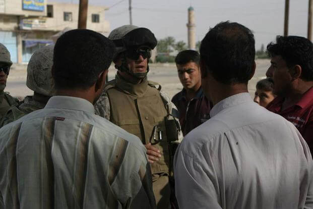 Major Mark Fuller, 2nd Team Commander, 2nd Detachment, 5th Civil Affairs Group talks through an interpreter to men at the local medical facility.( U. S. Marine Corps/ Lance Cpl. Athanasios L. Genos)