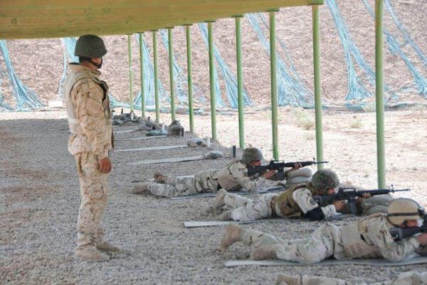 Iraqi Sgt. Mustafa watches as instructors from the Camp Taji Noncommissioned Officer Academy fire while qualifying with M-16 Rifles. (Photo Credit: Sgt. 1st Class Raymond Piper)