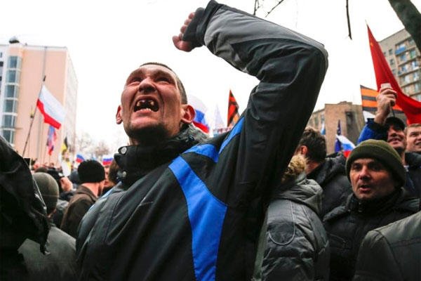 A pro-Russia demonstrator gestures as others storm the prosecutor-general's office during a rally in Donetsk, Ukraine, Sunday, March 16, 2014.