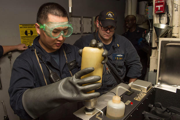 Engineman 2nd Class Changxuan Zhou, left, receives training from Chief Engineman Robert Carter on the combined contaminated fuel detector. (U.S. Navy photo by Mass Communication Specialist 2nd Class Joe Bishop)