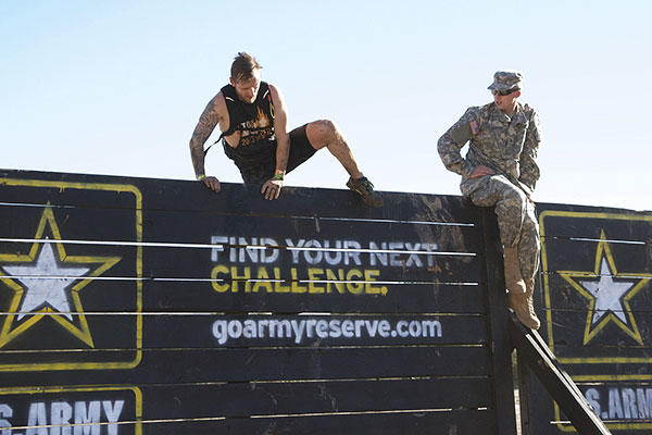 A competitor at the 2015 Southern California Tough Mudder competition in Temecula, Calif., Oct. 31, 2015, attempts the "Berlin Wall," one of the 21 obstacles in this year's event, flanked by Pfc. Dane E. Shoebotham. (U.S. Army photo)