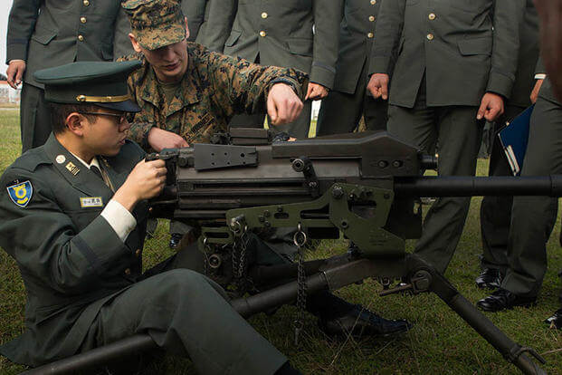 Pfc. Cooper Rottinghaus shows Japan Ground Self-Defense Force officer candidate Kazuhisa Takeda how to operate a MK19 machine gun, MOD 3 on Camp Kinser, Okinawa, Japan, Jan. 15. (Photo: Cpl. Robert D. Williams Jr.)