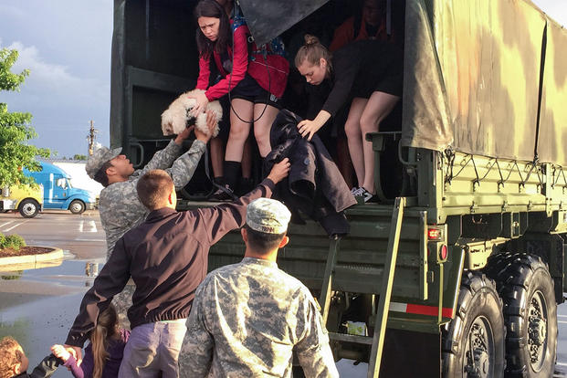 Soldiers help residents out the back of a high-water vehicle after severe flooding in Baton Rouge, La., Aug. 14, 2016. Guardsmen rescued more than 3,400 people and 400 pets since operations began Aug. 12. (Army National Guard photo)