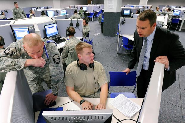 Master Sgt. Jesse Chervinka and Jessie Rhom help a cadet process an Electronic Questionnaire for Investigations Processing, or e-QIP, form.