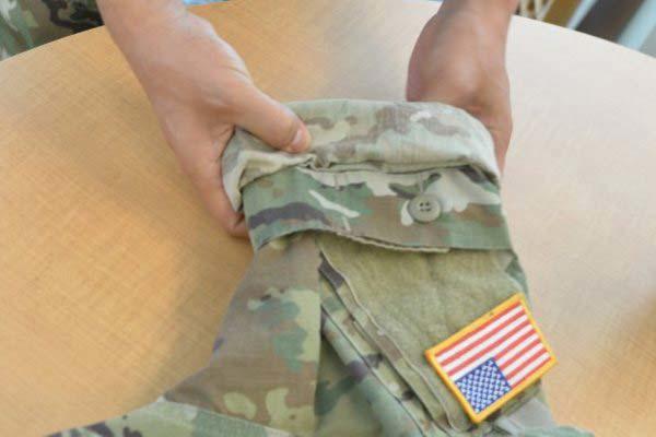A soldier demonstrates how to roll up the ACU sleeves so that the top portion can be pulled down over the roll for camo out. (Photo by Gary Sheftick/U.S. Army)