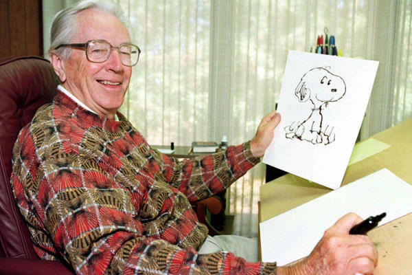 Charles Schulz holding a drawing of Snoopy.
