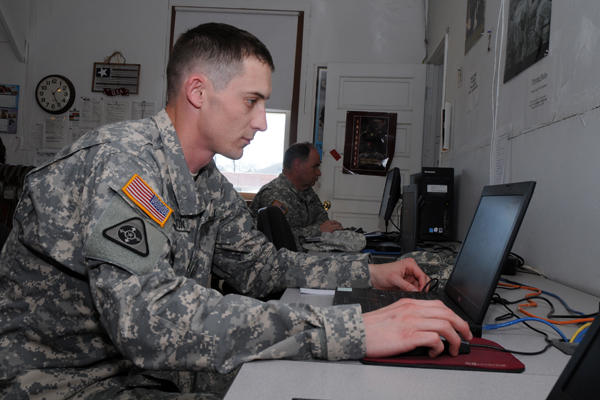 Servicemember using a laptop at a desk.