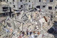 Palestinians look at the destruction after an Israeli airstrike in Rafah