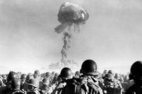 Members of the 11th Airborne Division kneel and watch a mushroom cloud stemming from an atomic bomb test at Frenchman’s Flat, Nevada Test Site, in November 1951. (Library of Congress)