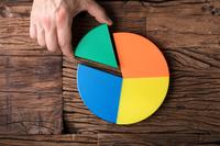 A hand places the fourth colored 'slice' into a pie-chart type of pie on a wood surface.