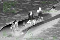 A Coast Guard MH-60 helicopter aircrew rescues three people