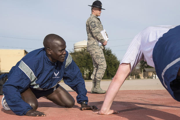 Guor Maker supports a wingman taking a physical fitness test Jan. 30, 2018 at the 324th Training Squadron’s physical training pad at Join Base San Antonio-Lackland, Texas. Maker was selected as a physical training leader for his time at BMT, his duties included leading the flight during warm-ups and providing support for struggling trainees. (U.S. Air Force/Dillon Parker)