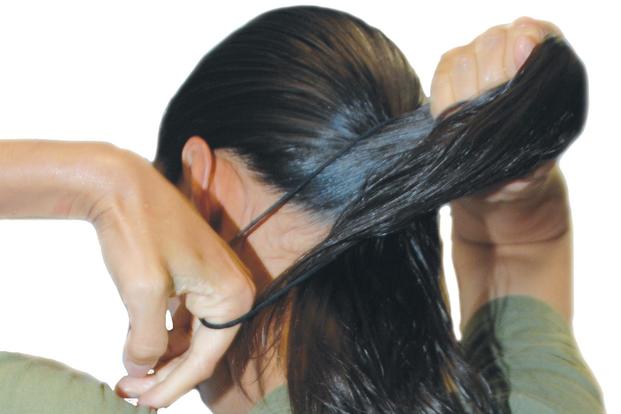  A female Marine demonstrates how to properly wrap her hair into a Marine Corps-standard bun. (U.S. Marine Corps/Pamela Jackson)