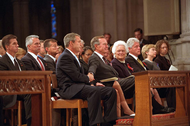 President George W. Bush grasps the hand of his father, former President George H.W. Bush, after speaking at the service for America’s National Day of Prayer and Remembrance at the National Cathedral in Washington, Sept. 14, 2001. (Photo by Eric Draper, Courtesy of the George W. Bush Presidential Library)