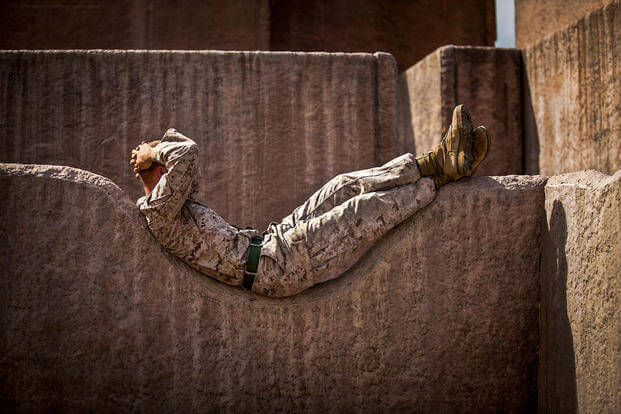 Marine Lance Cpl. Curtis E. Sledge relaxes on a rock wall before participating in a night raid on Marine Corps Base Hawaii, April 17, 2015. (U.S. Marine Corps photo by Lance Cpl. Aaron S. Patterson)
