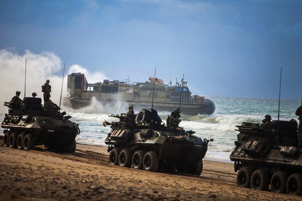 Marines with the 22nd Marine Expeditionary Unit convoy their light armored vehicles across the beach as a Navy air-cushion landing craft with Assault Craft Unit 4 departs the beach of Sierra del RetÌn, Spain, during a bilateral amphibious exercise with Spanish forces in February 2014. (US Marine Corps photo/Austin Hazard)