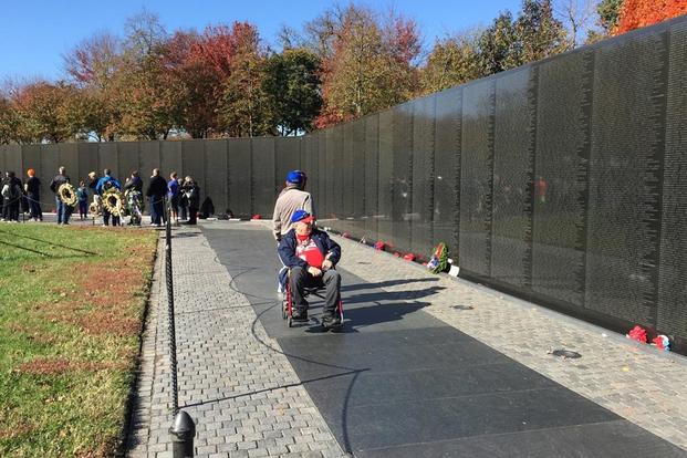 Mervin Olguin wheels Michael Owen, both Vietnam veterans, near the wall of names. (Oriana Pawlyk/Military.com)