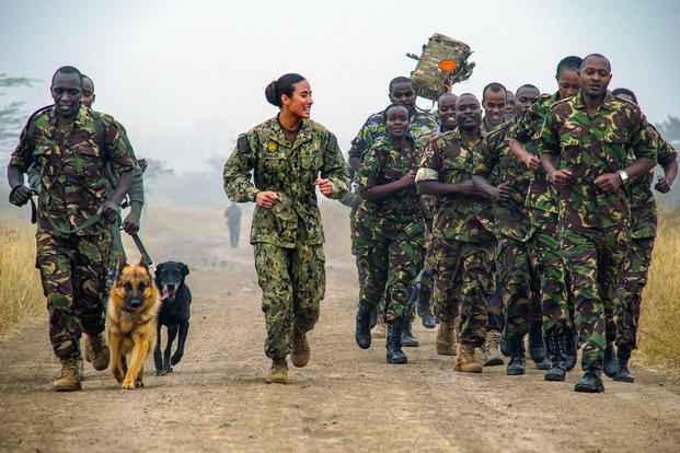 Navy Petty Officer 1st Class Kristina Vargas runs with members of the Kenya Defense Force's 1st Canine Regiment during a military working dog information exchange in Nairobi, Kenya, Aug. 9, 2018. (Air Force photo by Senior Airman Taylor Harrison)