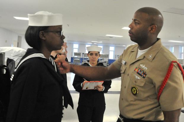 A recruit from participates in her final uniform inspection from Fleet Quality Assurance Inspector Petty Officer 1st Class Moses Brathwaite on Nov. 18, 2016 at Recruit Training Command. (U.S. Navy/Chief Petty Officer Seth Schaeffer).