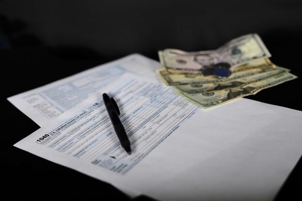  A 1040 tax form sits next to a small bit of cash. (U.S. Air Force/Senior Airman Valerie Halbert)