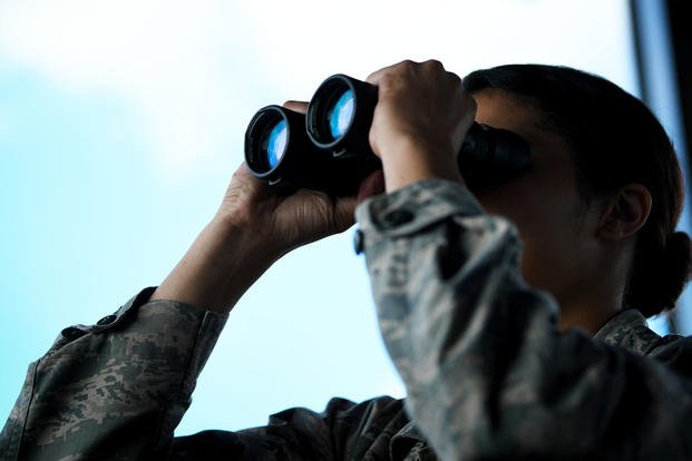 An airman uses binoculars.