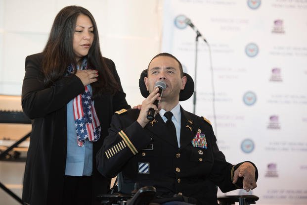 Army Capt. Luis Avila sings the National Anthem as his wife and caregiver Claudia looks on at the start of "A Day of Healing Arts: From Clinic to Community," an event honoring the importance of healing arts, during Warrior Care Month at National Harbor in Oxon Hill, Maryland on November 16, 2017. (DoD Photo/Roger L. Wollenberg)