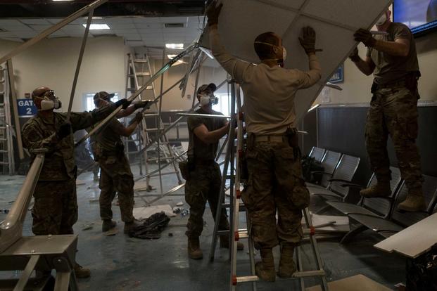 U.S. Air Force Airmen from the 405th Expeditionary Support Squadron remove damaged metal and ceiling tiles inside the passenger terminal the day after a Taliban-led attack on Bagram Airfield, Afghanistan, Dec. 12, 2019 (U.S. Air Force/Airman 1st Class Brandon Cribelar)