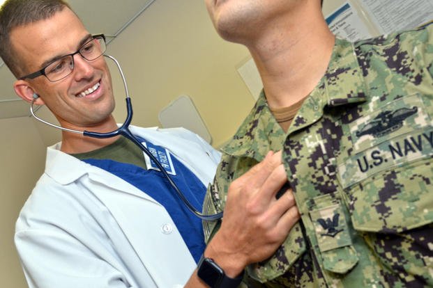 A doctor checks a sailor's heartbeat.